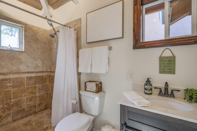 bathroom with tiled shower, vanity, and toilet