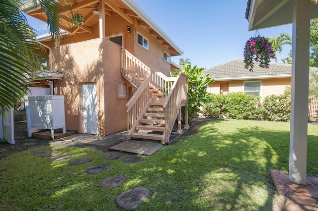 exterior space with stairs, a lawn, and stucco siding