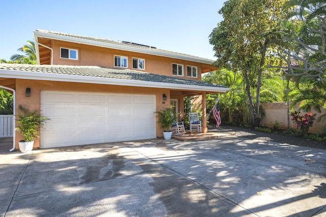 view of front facade featuring a garage, fence, concrete driveway, a tiled roof, and stucco siding