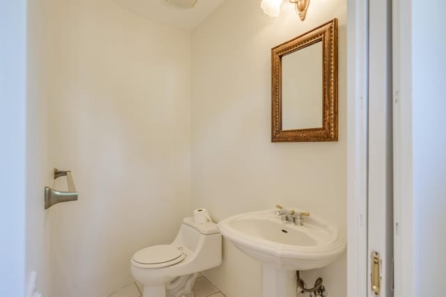 half bathroom featuring a sink, toilet, and tile patterned floors