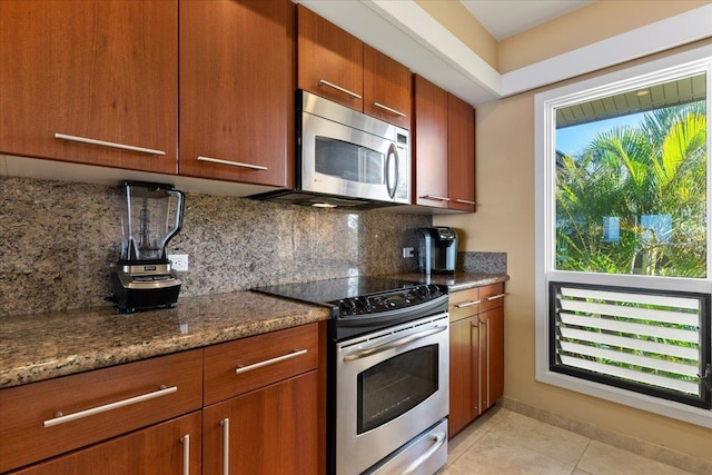 kitchen featuring dark stone counters, backsplash, light tile flooring, and stainless steel appliances