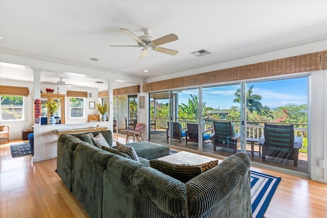 living room featuring ornate columns, light wood-type flooring, and ceiling fan