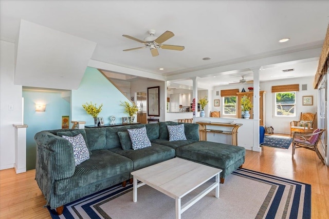 living room with light hardwood / wood-style floors, ceiling fan, and decorative columns