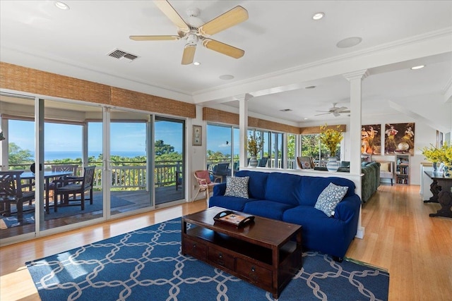 living room featuring a water view, hardwood / wood-style flooring, ceiling fan, and crown molding