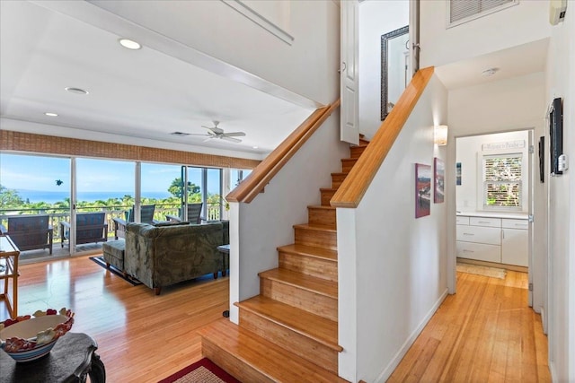 staircase with hardwood / wood-style flooring and ceiling fan