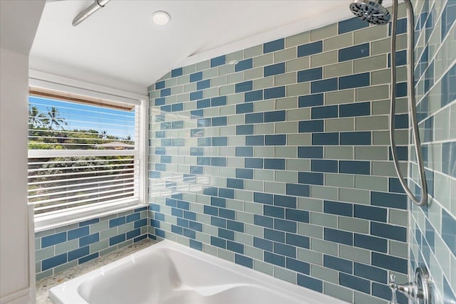 bathroom featuring tiled shower / bath combo, tile walls, and vaulted ceiling