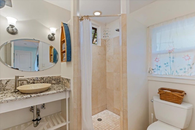 bathroom featuring sink, toilet, and a tile shower