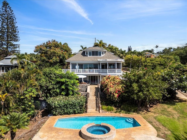 rear view of house featuring a pool with hot tub