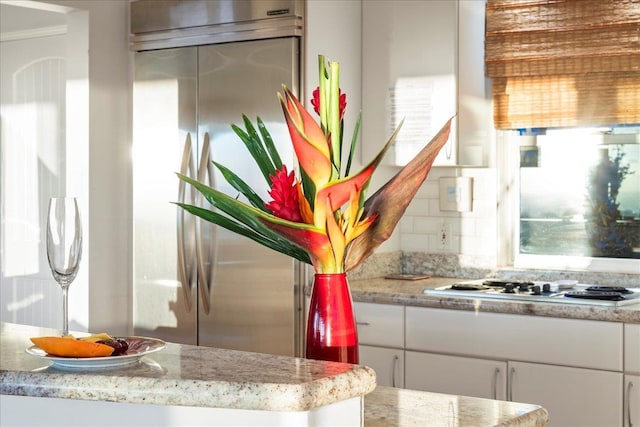 kitchen with white cabinets, white gas cooktop, a healthy amount of sunlight, and backsplash