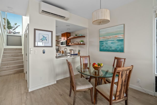 dining room featuring sink, light hardwood / wood-style flooring, and a wall mounted air conditioner