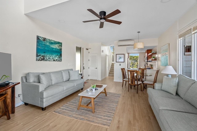 living room featuring an AC wall unit, light hardwood / wood-style floors, and ceiling fan