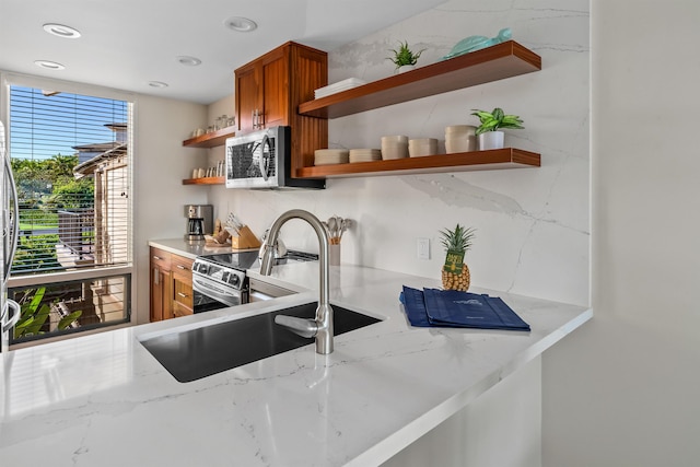 kitchen featuring sink, light stone counters, and appliances with stainless steel finishes