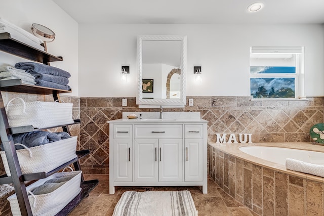 bathroom featuring vanity, tile walls, and a bath