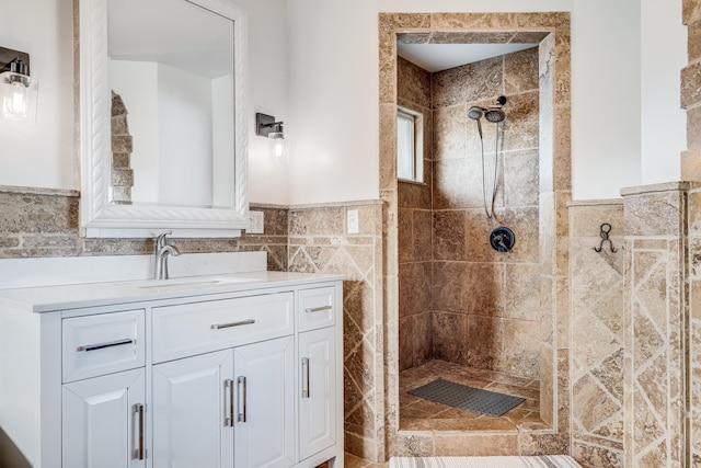 bathroom with vanity, tile walls, a wainscoted wall, and tiled shower