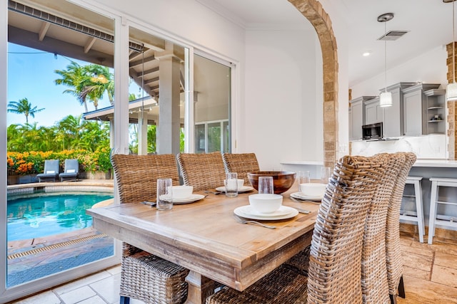 dining space featuring visible vents, recessed lighting, arched walkways, stone tile flooring, and crown molding