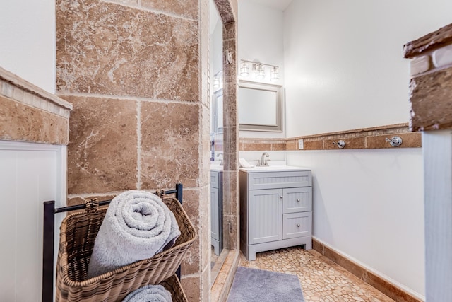 full bath with vanity, tile patterned flooring, a shower stall, wainscoting, and tile walls