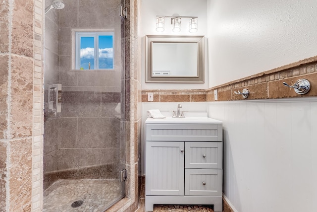 bathroom featuring wainscoting, a shower stall, and vanity