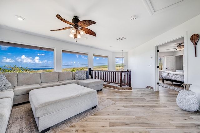 living room featuring a ceiling fan, light wood-style floors, and visible vents