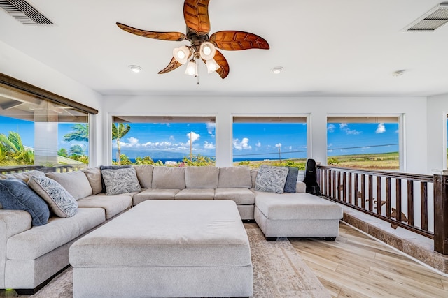 living area with visible vents, a ceiling fan, and wood finished floors