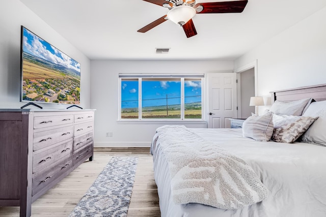 bedroom featuring a ceiling fan, visible vents, baseboards, and light wood-type flooring