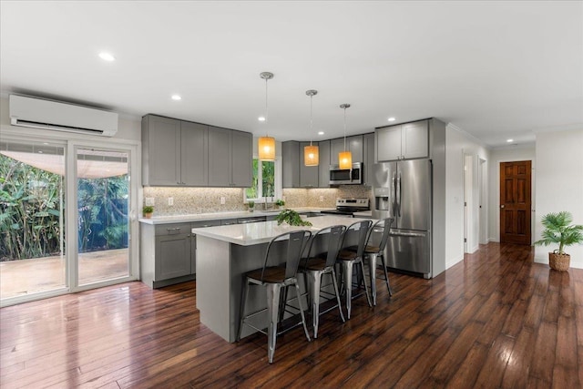 kitchen featuring stainless steel appliances, gray cabinets, pendant lighting, and a wall unit AC