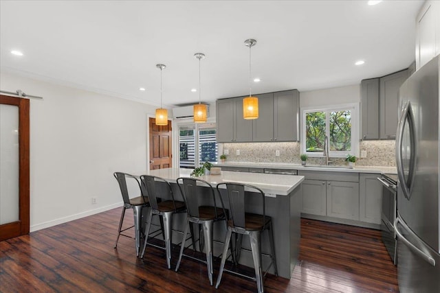 kitchen featuring gray cabinetry, tasteful backsplash, decorative light fixtures, appliances with stainless steel finishes, and a kitchen island