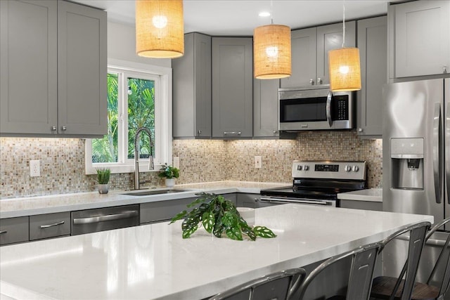 kitchen featuring appliances with stainless steel finishes, a breakfast bar, sink, and gray cabinetry