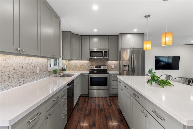 kitchen with sink, a kitchen island, gray cabinets, and appliances with stainless steel finishes