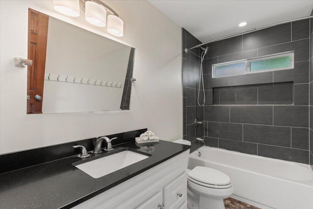 full bathroom featuring tiled shower / bath, vanity, and toilet