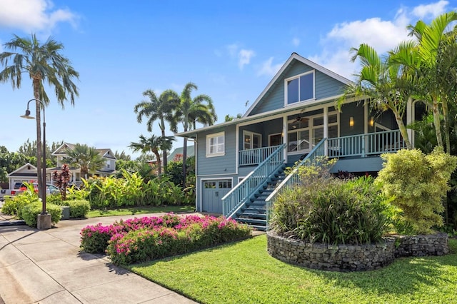 view of front facade featuring stairway, covered porch, a front yard, and ceiling fan