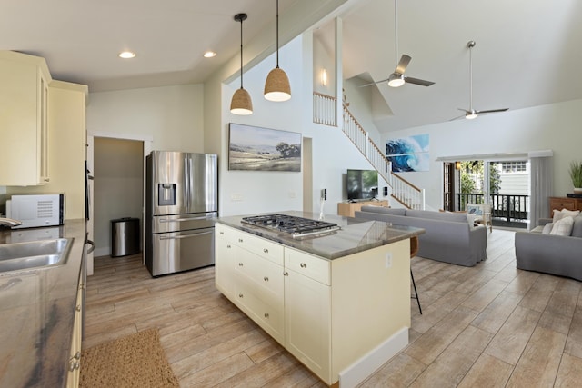 kitchen featuring wood finish floors, stainless steel refrigerator with ice dispenser, a sink, open floor plan, and white microwave