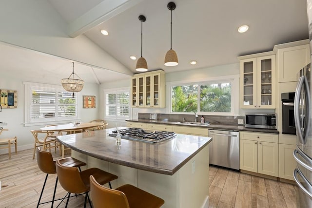 kitchen with light wood finished floors, appliances with stainless steel finishes, vaulted ceiling with beams, and a sink