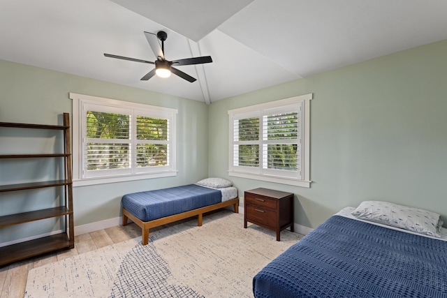 bedroom with baseboards, multiple windows, lofted ceiling, and wood finished floors