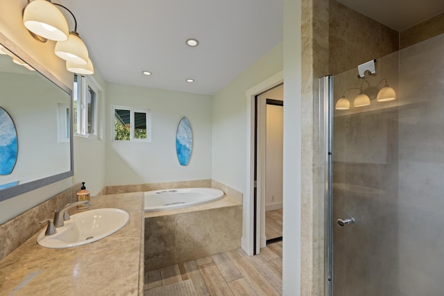 full bath with a garden tub, wood finished floors, a tile shower, recessed lighting, and vanity