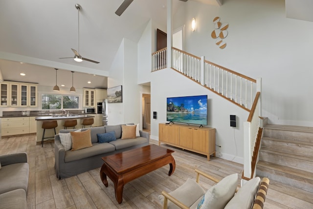 living area featuring stairway, light wood-type flooring, recessed lighting, high vaulted ceiling, and a ceiling fan