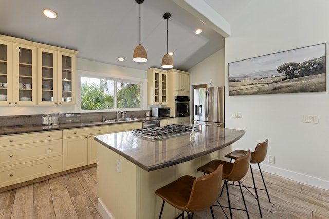 kitchen featuring a kitchen bar, cream cabinetry, light wood-style flooring, a center island, and stainless steel appliances