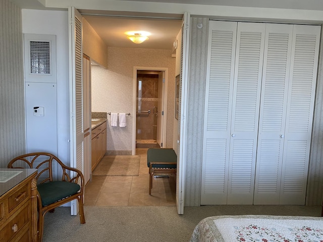 tiled bedroom with a closet and ensuite bathroom