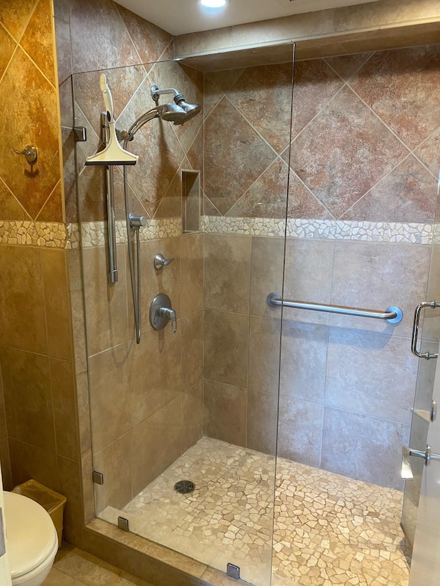 bathroom with a shower with door and toilet