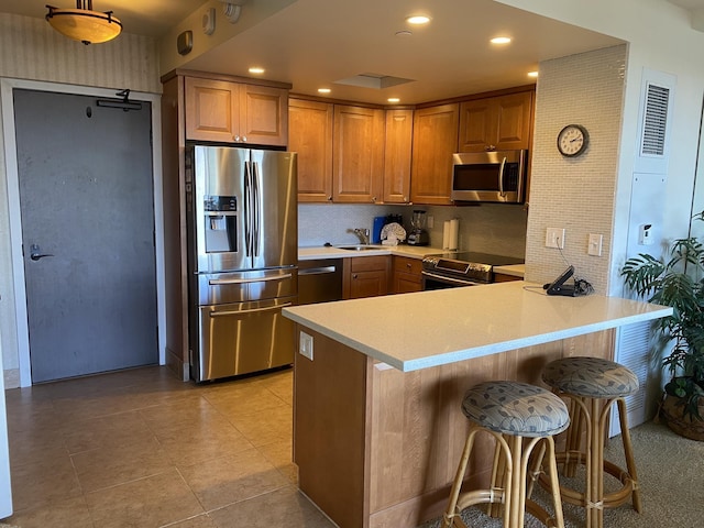 kitchen featuring sink, light tile patterned floors, stainless steel appliances, a kitchen bar, and kitchen peninsula