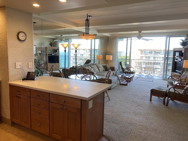 kitchen featuring pendant lighting, ceiling fan, beam ceiling, light colored carpet, and kitchen peninsula