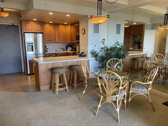 kitchen featuring pendant lighting, kitchen peninsula, a kitchen breakfast bar, and stainless steel fridge with ice dispenser