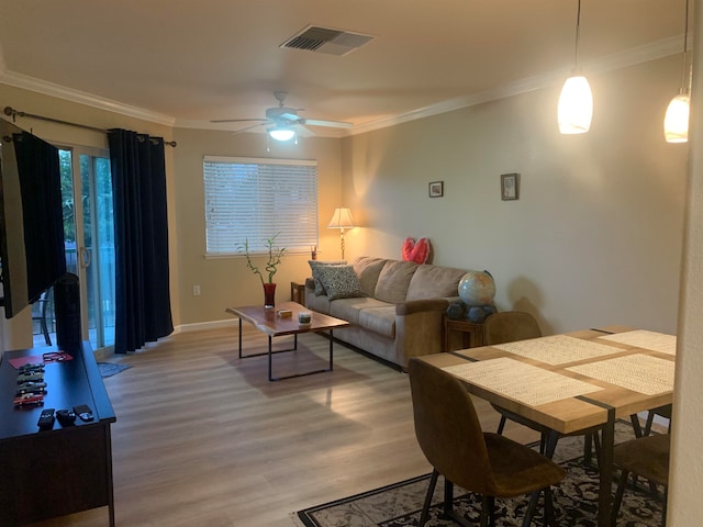 living room featuring ornamental molding, light hardwood / wood-style floors, and ceiling fan