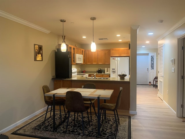 dining space with crown molding, light hardwood / wood-style floors, and sink