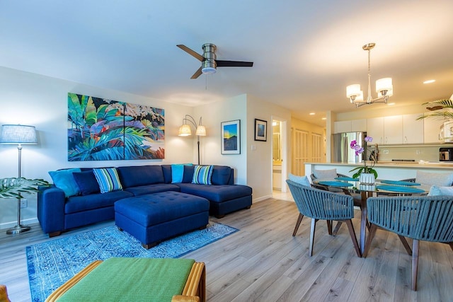 living room with ceiling fan with notable chandelier and light wood-type flooring