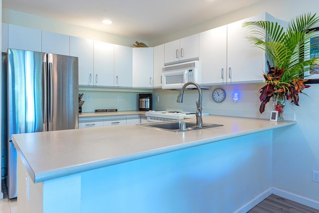 kitchen featuring white cabinets, stainless steel fridge, kitchen peninsula, and sink