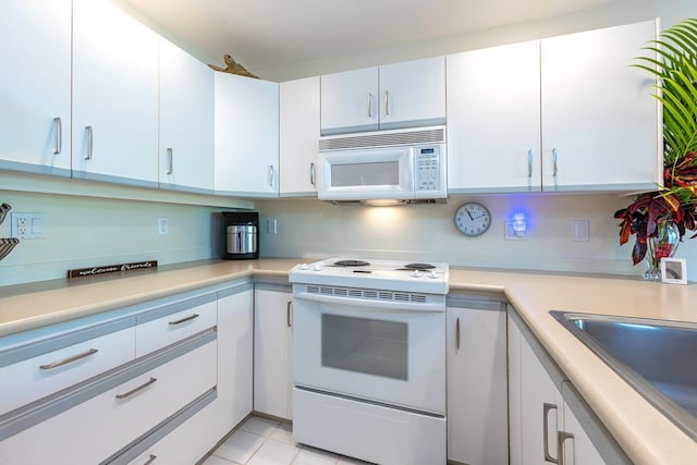 kitchen featuring sink, white cabinets, light tile patterned flooring, and white appliances