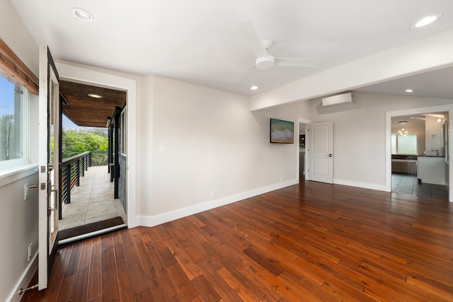 unfurnished room with vaulted ceiling, ceiling fan, dark hardwood / wood-style flooring, and a wall mounted air conditioner