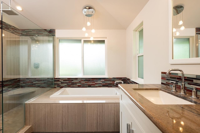 bathroom featuring vanity, independent shower and bath, and lofted ceiling