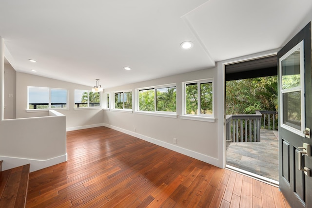 spare room with hardwood / wood-style floors, vaulted ceiling, and plenty of natural light