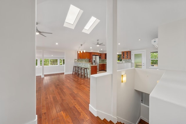 interior space with vaulted ceiling with skylight and wood-type flooring